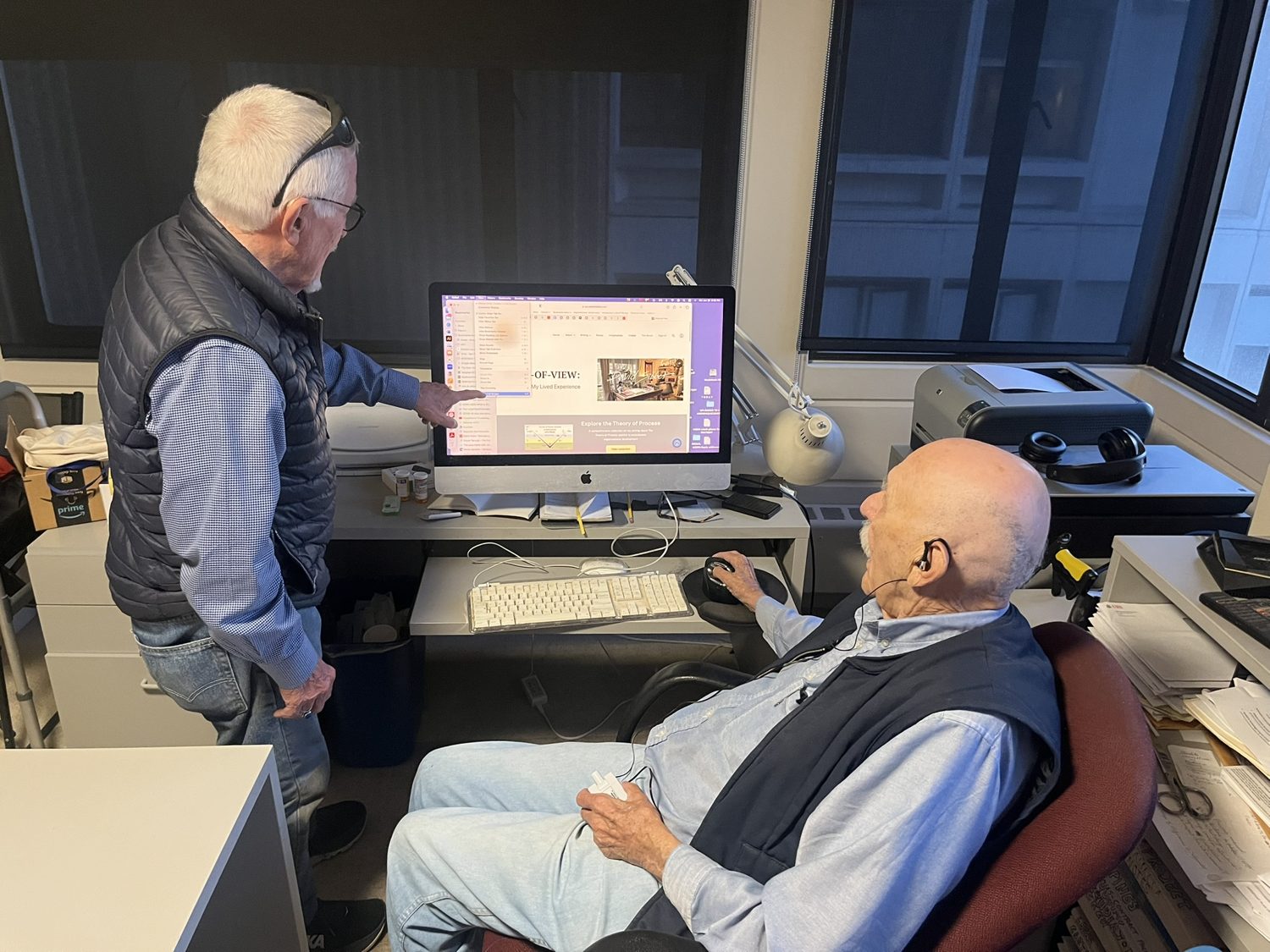 David Sibbet standing and pointing at a screen while Bob Horn sits beside him in the studio