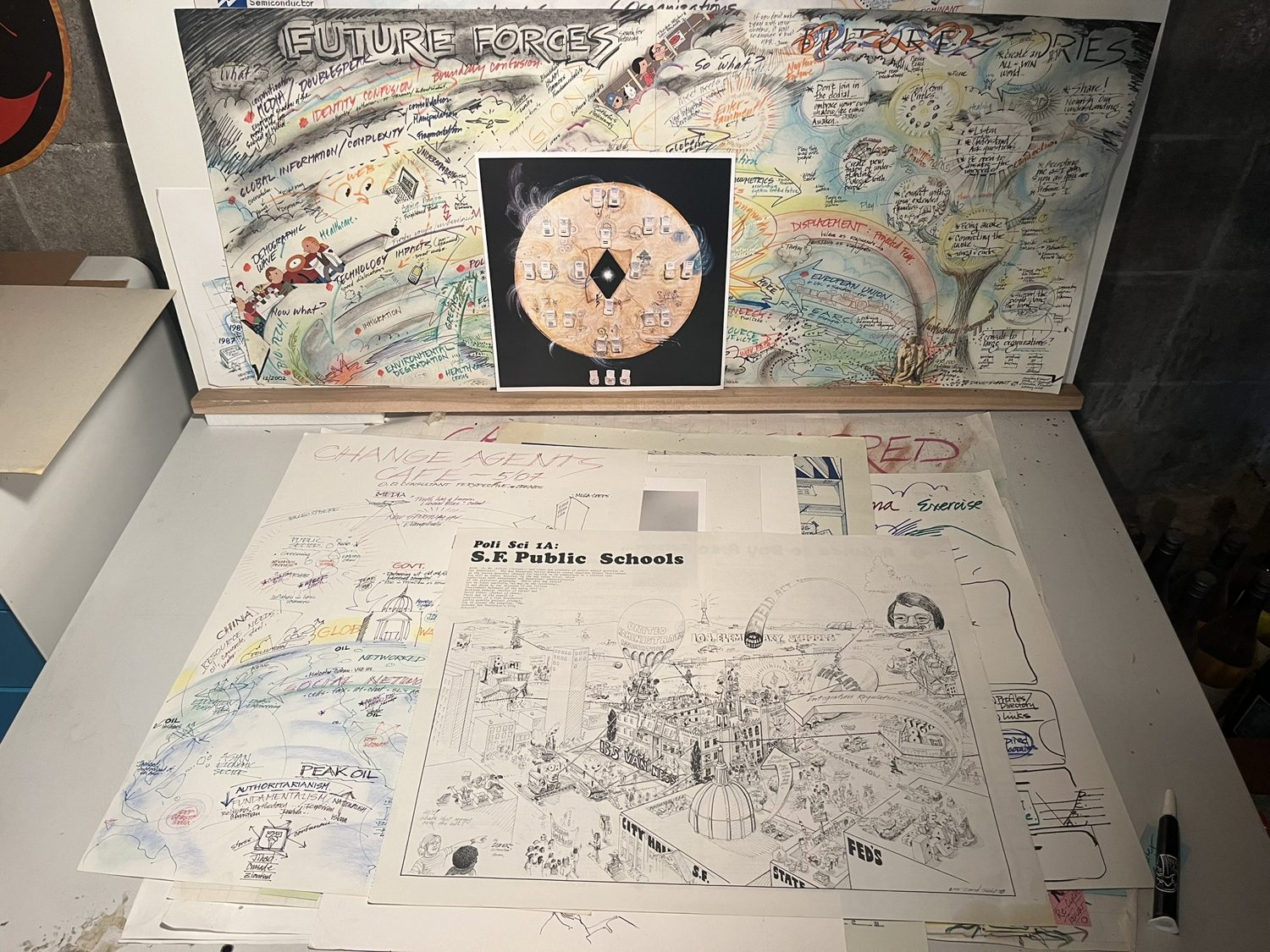 Early works on the table, including a Future Forces map and a San Francisco public schools map